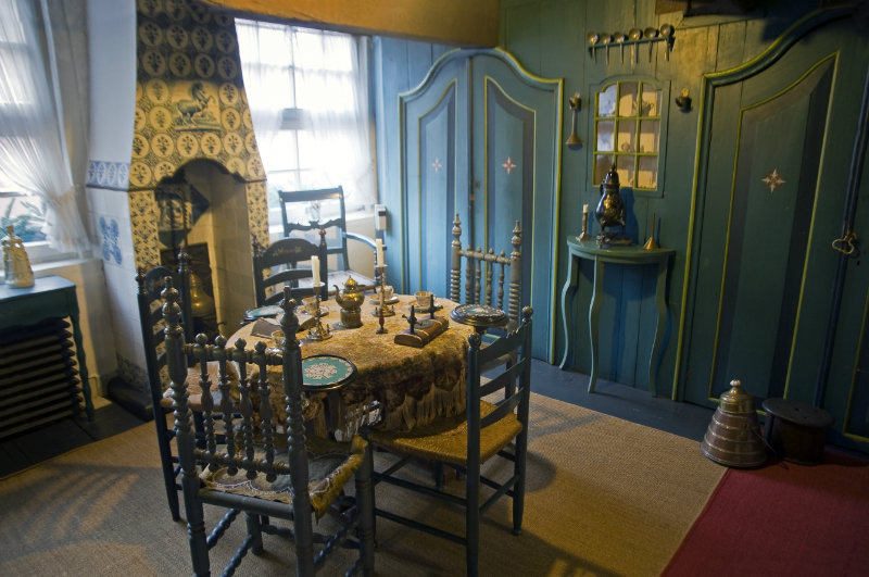 Museum: Ein Essbereich mit gr&uuml;ner Wandvert&auml;felung, einem dekorierten Tisch, traditionellen St&uuml;hlen und einer antiken Einrichtung im friesischen Stil.